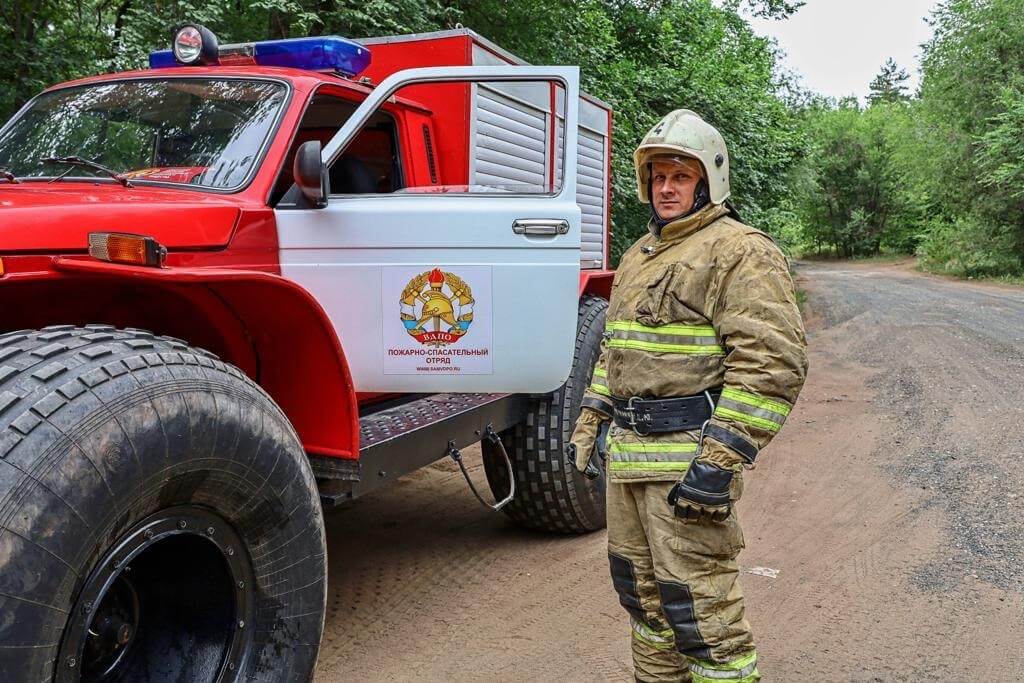 Пожарный добровольного отряда рядом с пожарной техникой